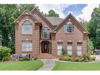 Charming two-story brick home with arched windows and a well-manicured lawn at 380 Chandler Ct, Sugar Hill, GA 30518