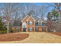 Traditional brick home with black shutters, manicured lawn, and a large front window at 11910 Wildwood Springs Dr, Roswell, GA 30075
