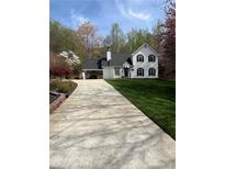 Charming two-story home featuring a manicured lawn, and long driveway at 5130 Forest Hills Ct, Cumming, GA 30041