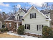 Charming home with sage green siding, black shutters and a brick facade, set on a manicured lawn at 1213 Fairwinds Dr, Loganville, GA 30052