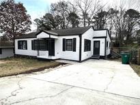 Charming home featuring a white exterior with black trim, a concrete driveway, and a well-maintained front yard at 1298 Belmont Se Ave, Smyrna, GA 30080