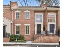 Charming brick townhome featuring large windows, landscaped entrance, and inviting front steps at 604 Ansley Villa Ne Dr, Atlanta, GA 30324