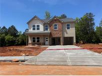 Two-story home featuring brick and vinyl siding with an attached two-car garage and newly poured concrete driveway at 1590 Sungrown Way, Mcdonough, GA 30253