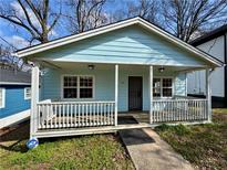 Charming, light blue, one-story home featuring a cozy, covered front porch with white railings at 958 Fern Se Ave, Atlanta, GA 30315