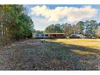 Spacious front yard featuring a mobile home with a covered porch, surrounded by trees at 1515 Ozora Rd, Loganville, GA 30052