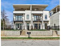 Modern townhome with white brick, black trim, balconies, and a small front yard at 1100 Arkwright Se Pl # B, Atlanta, GA 30316