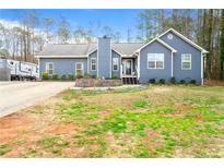 Charming blue home featuring a well-manicured lawn, detailed landscaping, and inviting front porch at 1788 Jefferson Ln, Douglasville, GA 30134