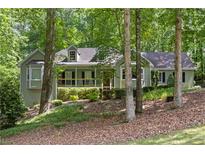 Charming, light green home with a welcoming front porch and lush, wooded surroundings on a naturally landscaped lot at 90 Lakeside Dr, Hiram, GA 30141