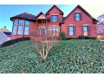 Charming red brick two-story home with manicured lawn, dark shutters, and a bay window at 11365 Donnington Dr, Duluth, GA 30097