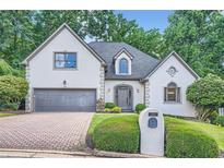 Charming two-story home with a well-manicured lawn, stone accents, and a brick driveway at 140 Grosvenor Pl, Atlanta, GA 30328