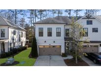 Charming townhome featuring a two-car garage and a neatly landscaped front yard on a sunny day at 411 Johnson Ct, Alpharetta, GA 30009