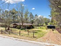 Ranch style home with a long driveway, large front yard, and some mature trees at 4544 Ridgeview Dr, Powder Springs, GA 30127