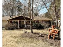 Charming single-story brick home featuring a cozy front porch, a well-manicured yard, and unique garden art at 4544 Ridgeview Dr, Powder Springs, GA 30127
