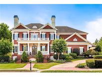 Stately brick home featuring a columned front porch, manicured lawn, and lush landscaping at 1010 Lancaster Sq, Roswell, GA 30076