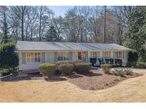 Charming one-story home featuring a brick facade, shuttered windows, and manicured landscaping at 4630 Canyon Creek Trl, Atlanta, GA 30342