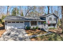 Charming blue two-story home with an attached garage, landscaped yard, and inviting entrance at 3594 Vinyard Way, Lawrenceville, GA 30044