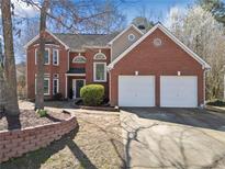 Charming two-story brick home featuring a two-car garage and well-manicured landscaping in a suburban setting at 7104 Big Woods Dr, Woodstock, GA 30189