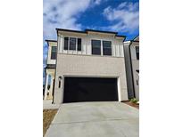 Modern two-story home featuring a two-car garage and a mix of brick and board and batten siding at 990 Sutherland Lane (Lot 34), Lawrenceville, GA 30043