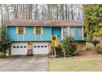 Charming, blue, split-level home featuring a bright yellow door and shutters, stone accents, and a well-manicured lawn at 2578 Scalpem Ct, Duluth, GA 30096