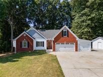 Charming brick and white home featuring a three-car garage and well-manicured lawn at 2957 Berry Rd, Loganville, GA 30052