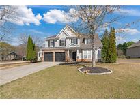 Charming two-story home featuring a stone facade, black garage doors, and well-maintained landscaping on a sunny day at 3130 Caney Creek Ln, Cumming, GA 30041