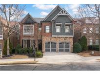 Beautiful two-story home featuring brick, stone, and gray shingle siding with a well-manicured front yard and a two-car garage at 13029 Dartmore Ave, Alpharetta, GA 30005