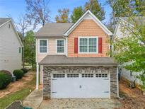 Charming home featuring a stone-accented two-car garage, symmetrical windows and red shutters at 2521 Capella Sw Cir, Atlanta, GA 30331