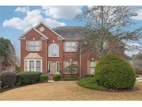 Beautiful two-story brick home featuring a manicured lawn and mature landscaping at 2615 Springmonte Pl, Cumming, GA 30041