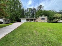 Charming single-story home with a well-manicured lawn, lovely landscaping and a long driveway at 371 Landers Sw Dr, Mableton, GA 30126