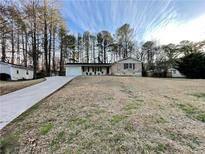 Ranch-style home with long driveway and a mix of brick and vinyl siding, set against a backdrop of tall trees at 371 Landers Sw Dr, Mableton, GA 30126