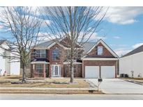 Charming two-story red brick home with attached two-car garage and well-manicured front yard in a suburban neighborhood at 30 Oak Manor Dr, Covington, GA 30016