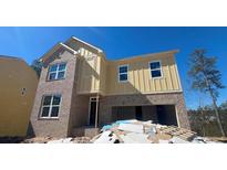 Two-story brick home with a two-car garage and a yellow wood facade under construction at 630 Gilles Ln, Cumming, GA 30041