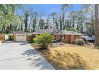 Charming single-story brick home featuring a well-manicured lawn and a detached two-car garage with a freshly-poured concrete driveway at 3551 Dial Dr, Stone Mountain, GA 30083