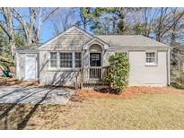 Charming single-story home featuring a painted brick facade, inviting front porch, and mature trees at 1542 Columbia Dr, Decatur, GA 30032