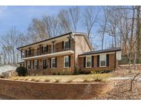 Traditional brick home featuring a second-story balcony, black shutters, and a well-maintained lawn at 2597 Churchwell Ln, Tucker, GA 30084