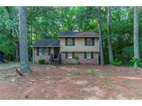 Two-story home featuring brick and siding, a wooded lot, and a quaint front porch at 4342 Lincolndale Dr, Ellenwood, GA 30294