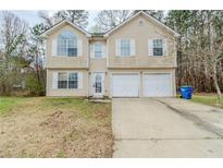 Beige two-story home with a two-car garage and front lawn at 445 Skif Pond Ct, Atlanta, GA 30349