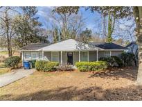 Charming gray brick home with a well-manicured lawn and lush greenery at 2973 Cambridge Sw Dr, Atlanta, GA 30331