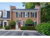 Charming brick townhouse with black shutters, manicured bushes, and a red door at 6 Walnut Hill Nw Pl, Atlanta, GA 30318
