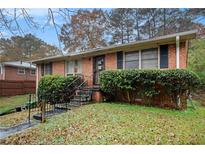 Charming brick home with manicured bushes and iron railing leading to the front door at 569 Oakside Sw Dr, Atlanta, GA 30331