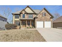 Charming two-story home with a stone and yellow siding exterior and a two-car garage at 70 Wentworth Ln, Villa Rica, GA 30180