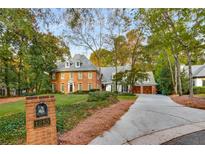 Charming brick home with manicured lawn and mature trees on a sunny day at 1285 Wesley Nw Pl, Atlanta, GA 30327