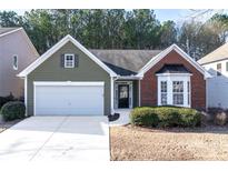 Charming one-story home with a brick facade, green siding, well-manicured yard, and attached garage at 3280 Cooper Woods Dr, Loganville, GA 30052