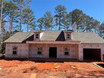 New home featuring dormer windows and an attached garage, set against a backdrop of lush trees and a bright, clear sky at 8141 Hickory Dr, Covington, GA 30014