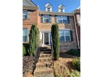 Brick townhome with dormer windows, front door and landscaped front with stairs at 4215 Wildener Way, Cumming, GA 30041