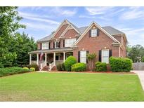 Charming brick home with manicured lawn, covered porch, and lush landscaping at 235 Rippling Nw Dr, Marietta, GA 30064