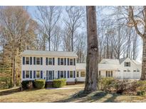 Charming two-story home with blue shutters, a well-manicured lawn, and a detached three car garage at 5322 Seaton Dr, Dunwoody, GA 30338