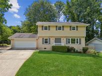 Charming two-story home with a well-manicured lawn, attached garage, and neutral color palette surrounded by mature trees at 1231 Sanden Ferry Dr, Decatur, GA 30033