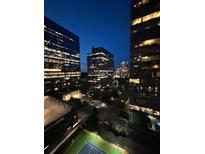 Night view of modern high-rise buildings featuring illuminated windows, city street, and a tennis court at 3445 Stratford Ne Rd # 1605, Atlanta, GA 30326