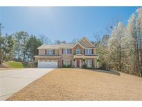 Charming two-story home with stone accents, red shutters, attached garage, and well-maintained lawn at 9225 Wilshire Pl, Cumming, GA 30028
